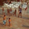 Persone partecipano a una lezione di ginnastica in una piazza con sedie bianche.
