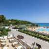 Vista di una piscina con ombrelloni arancioni e tavoli all'aperto vicino al mare.