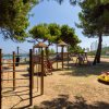 Parco giochi all'aperto vicino al mare, circondato da alberi.