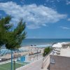 Piscina e spiaggia con ombrelloni blu.