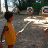 Bambino mira a bersagli con arco in un campo.
