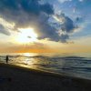 Spiaggia al tramonto con persone che camminano sulla sabbia.