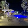Piscina illuminata di sera con sedie a sdraio e ombrelloni.