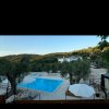 Piscina con vista panoramica su colline alberate e ombrelloni bianchi.
