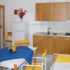 Cucina moderna con tavolo bianco, sedie gialle e un divano.