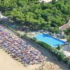 Spiaggia con ombrelloni colorati e un'area alberata con piscina.