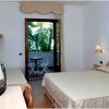 Camera da letto con letto matrimoniale e balcone con sedie bianche.