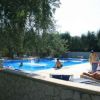 Piscina all'aperto di giorno con persone che nuotano e prendono il sole.