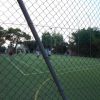 Partita di calcetto su un campo all'aperto, vista attraverso una rete.