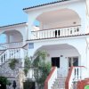 Villa bianca a tre livelli con balconi, scale e piante.