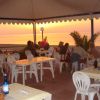 Persone cenano sotto un tendone al tramonto.