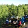 Tenda blu e verde tra alberi, persone in piedi.